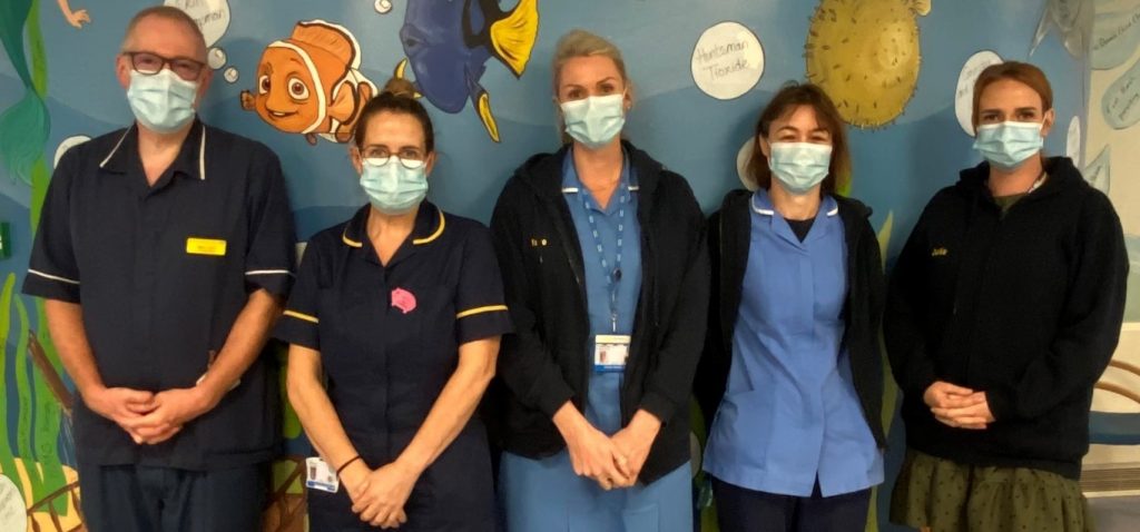 Staff from the Hospital at Home team stood in front of a wall