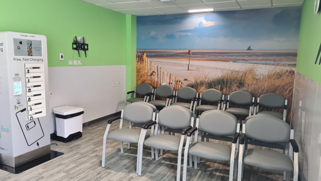 A freestanding multi-phone charger stands in an area of the new Grimsby Emergency Department.
A mural showing a view out over the Humber from Cleethorpes is displayed on the back wall