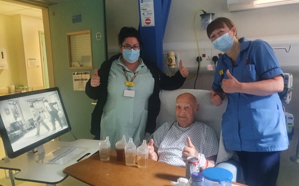 Two women stood next to a man in bed with their thumbs up