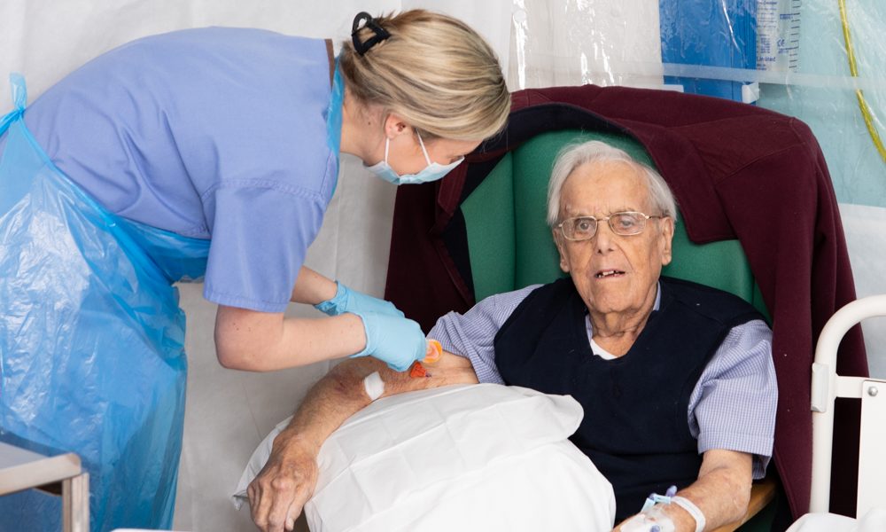 A patient sitting in a chair as one of our nurses tends to him