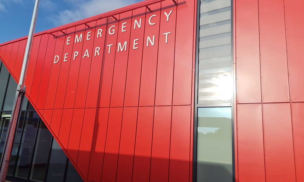 The exterior of the new Grimsby Emergency Department. The building is clad in red and has floor to ceiling windows surrounding the door
