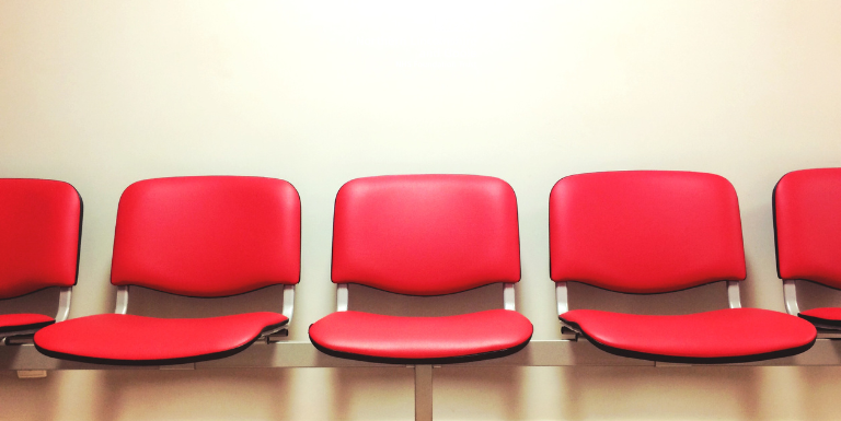 row of empty red chairs in a waiting room