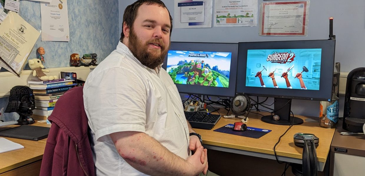 A man sat in front of two computer screens showing Minecraft and Surgeon Simulator 2.