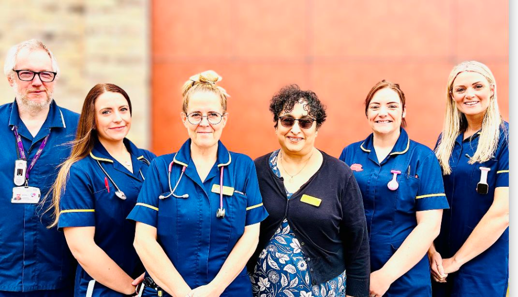 A man and five women stood outside smiling. Most of them are in nursing uniforms.