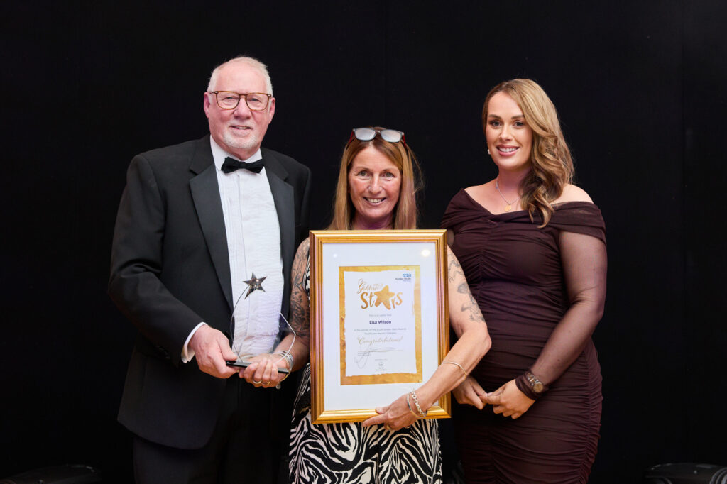 a woman holding a golden framed certificate with a man holding a trophy and another woman