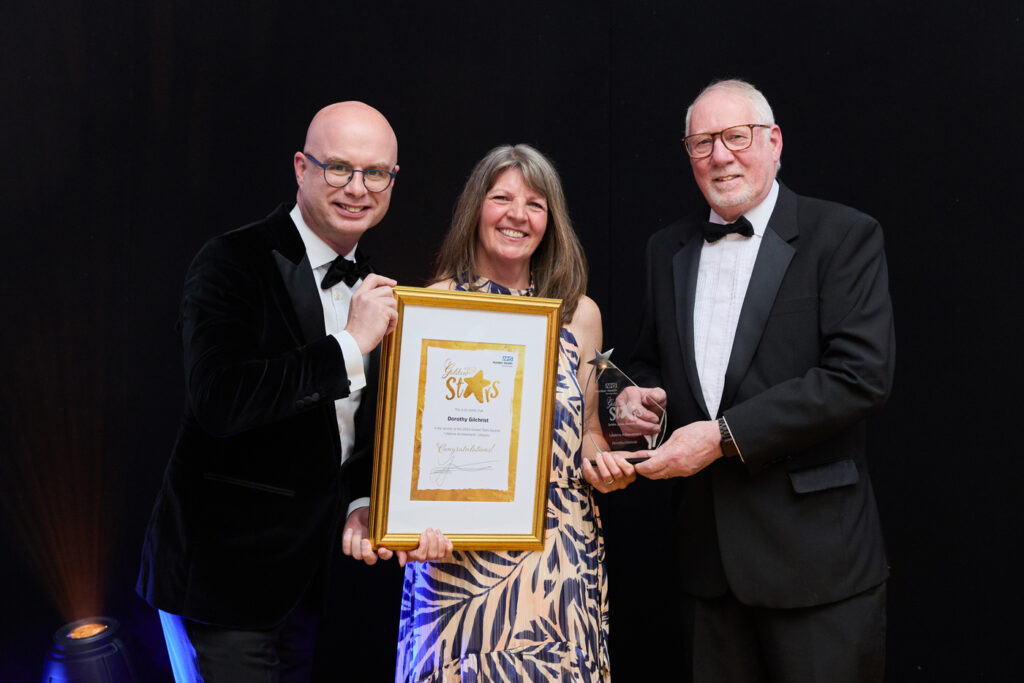 a woman holding a golden framed certificate with a man holding a trophy and another man