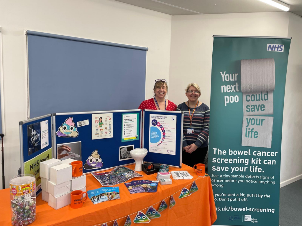 Louise Bond, Specialist Screening Practitioner, and Faye Wooler, Administrator, stand in front of their display promoting bowel cancer screening