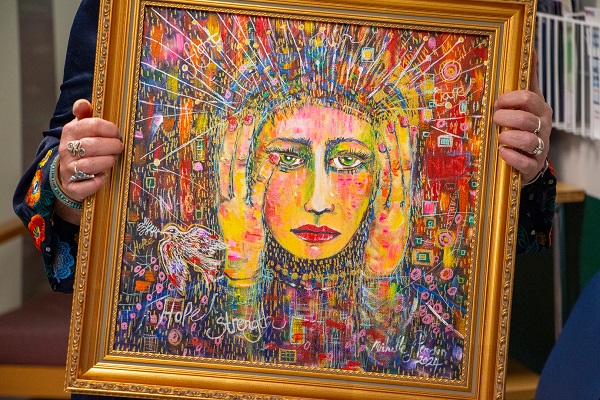 Artwork by Michelle Pearson in vivid colours including red, yellow, green and purple showing a woman with her head in her hands surrounded by colour and words including hope, strength, care and NHS