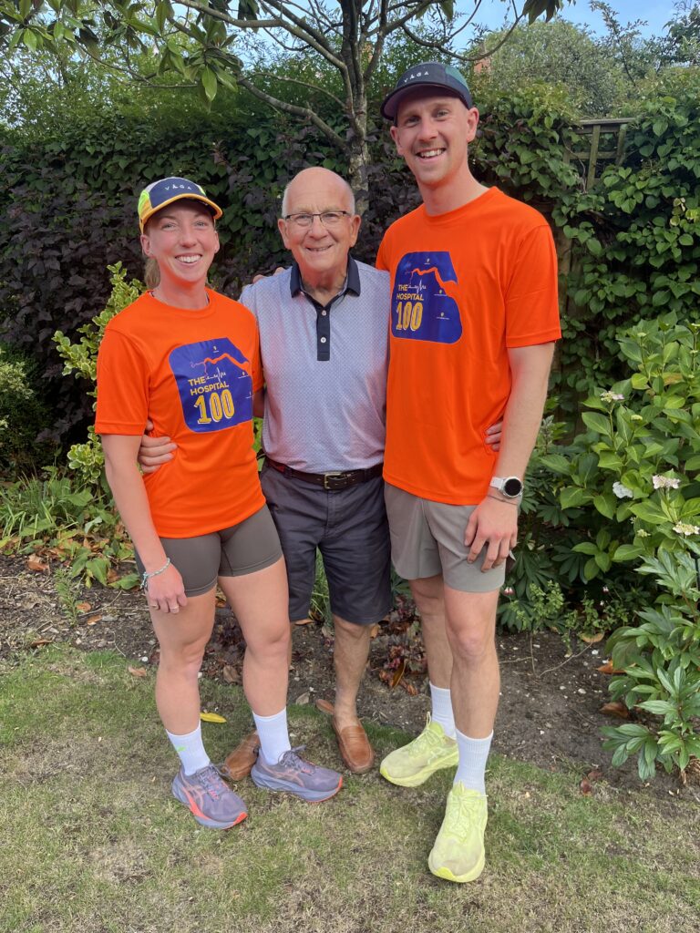 A man and woman wearing running gear, pictured with a man in the middle