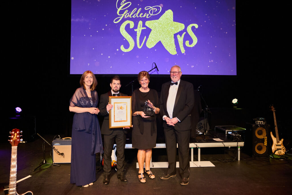 a group of people on a stage with a certificate or trophy