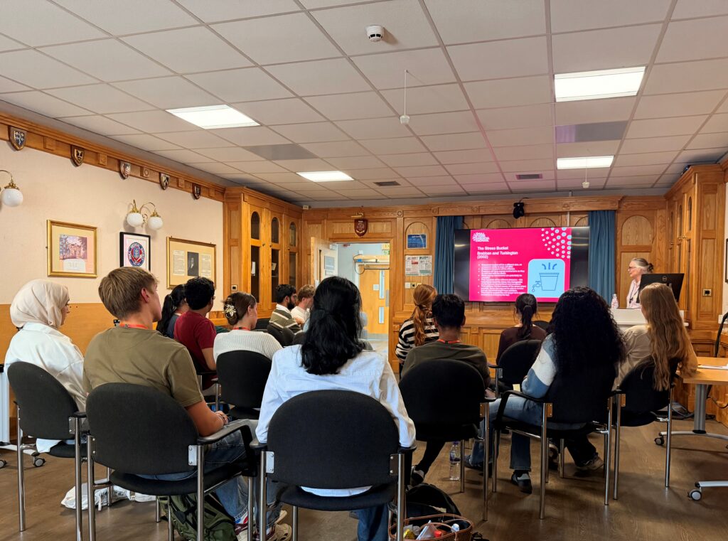 A group of people in a room listening to a speaker