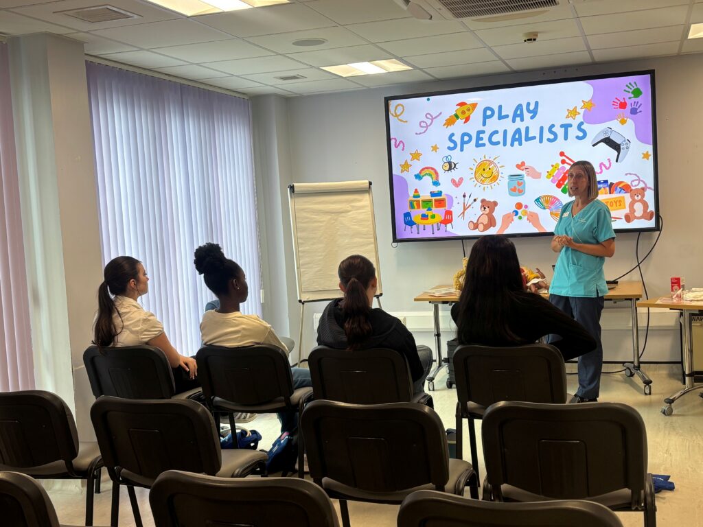 A group of healthcare students listening to a Play Specialist talking