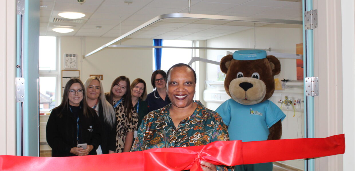 A woman cutting a ribbon with charity and NHS staff stood behind her