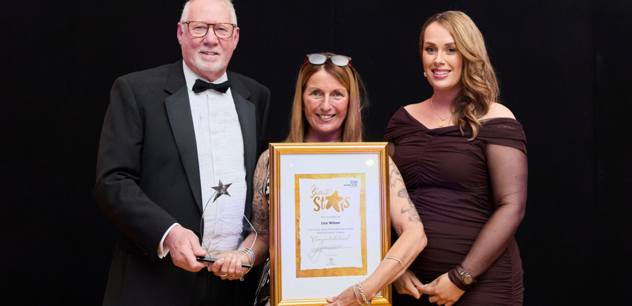 a woman holding a golden framed certificate with a man holding a trophy and another woman
