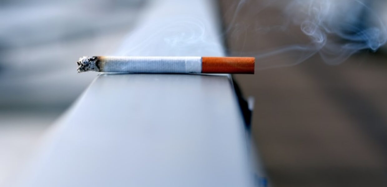 A smoking cigarette is placed on a handrail