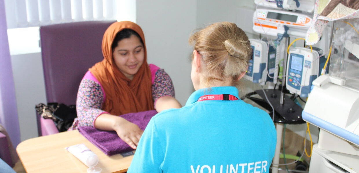 A woman getting a hand massage in hospital from a volunteer