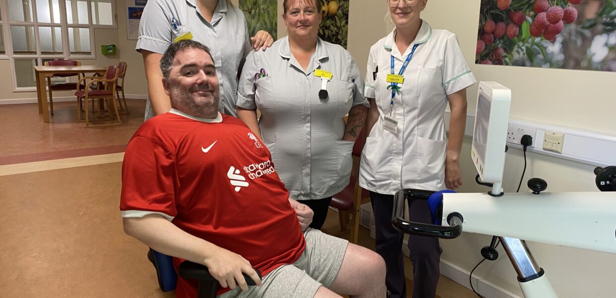 A man in a wheelchair pictured with hospital staff
