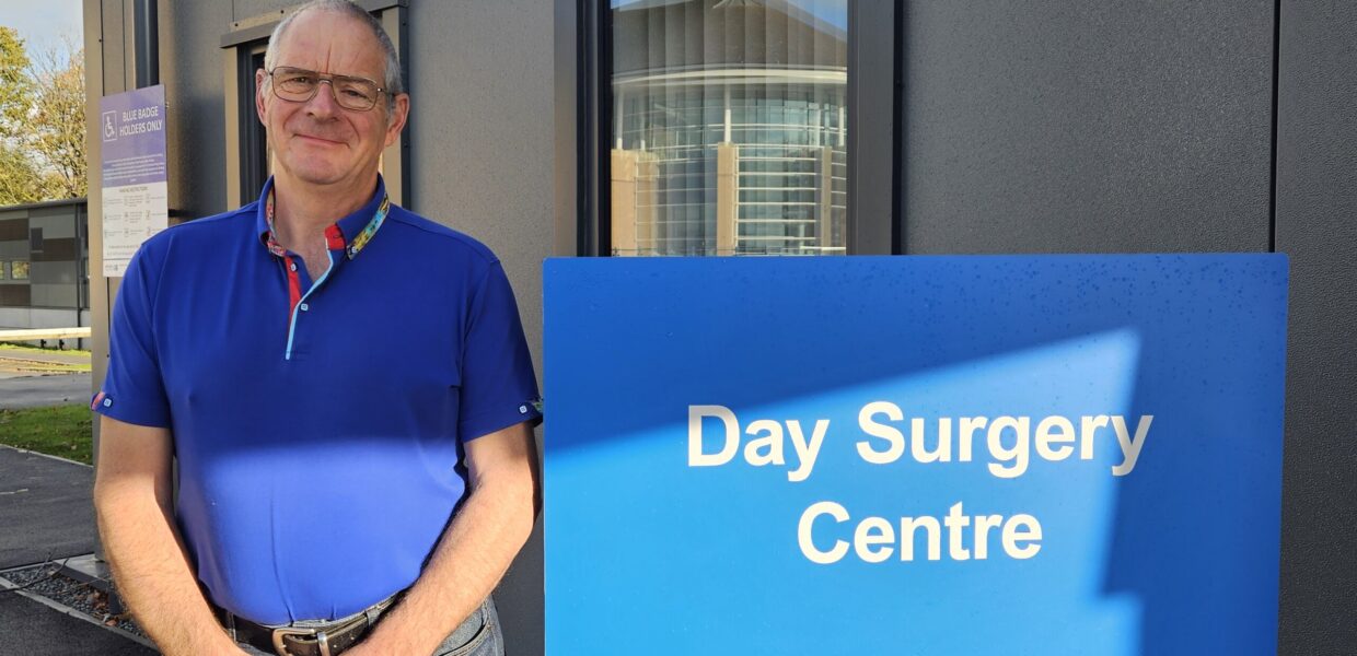 A man stood next to a sign saying "Day Surgery Centre"