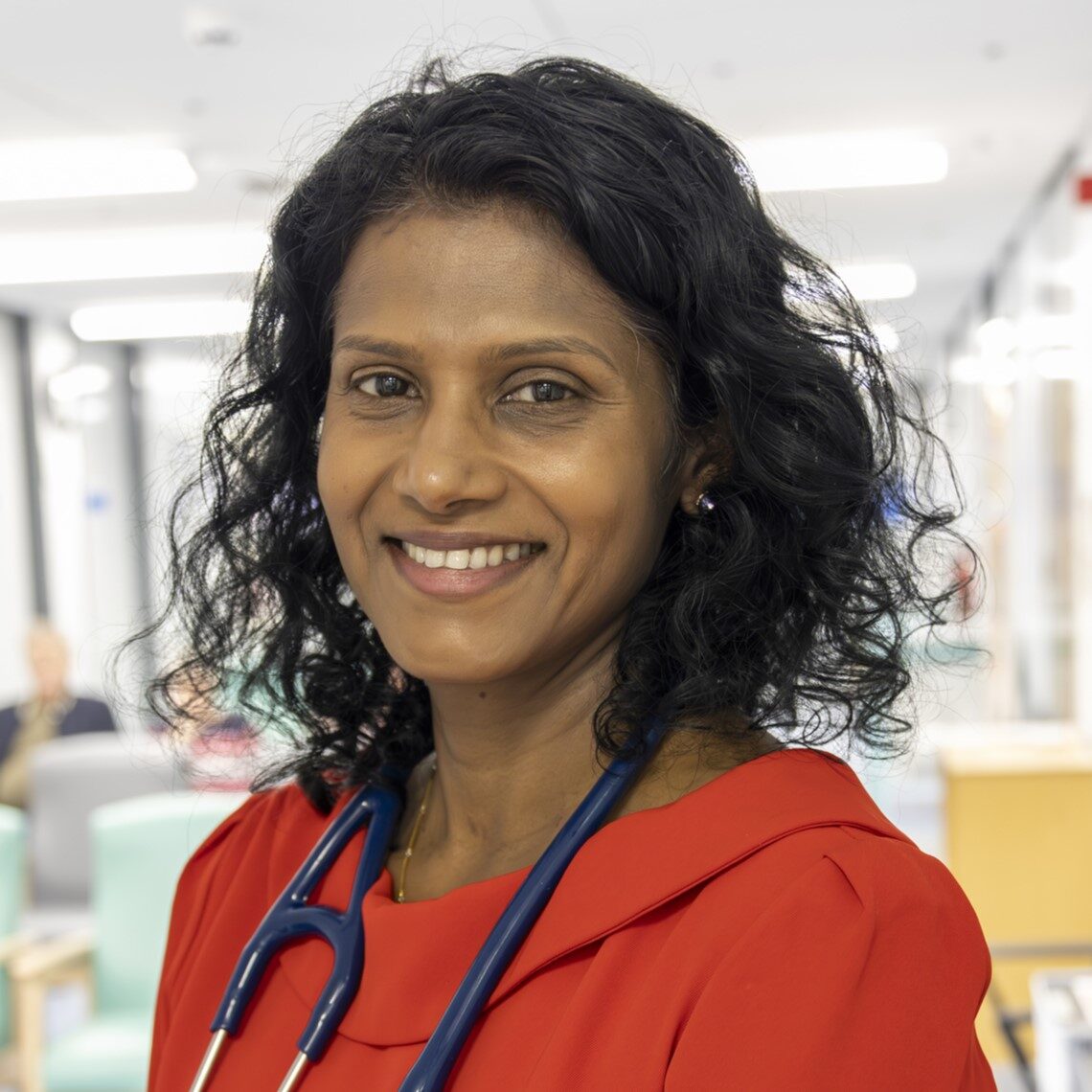 Portrait image of Dr Sasi Pathmanathan. She wears a red dress and a stethoscope around her neck.