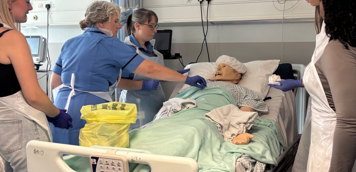 A group of healthcare students stood around a manikin in a bed