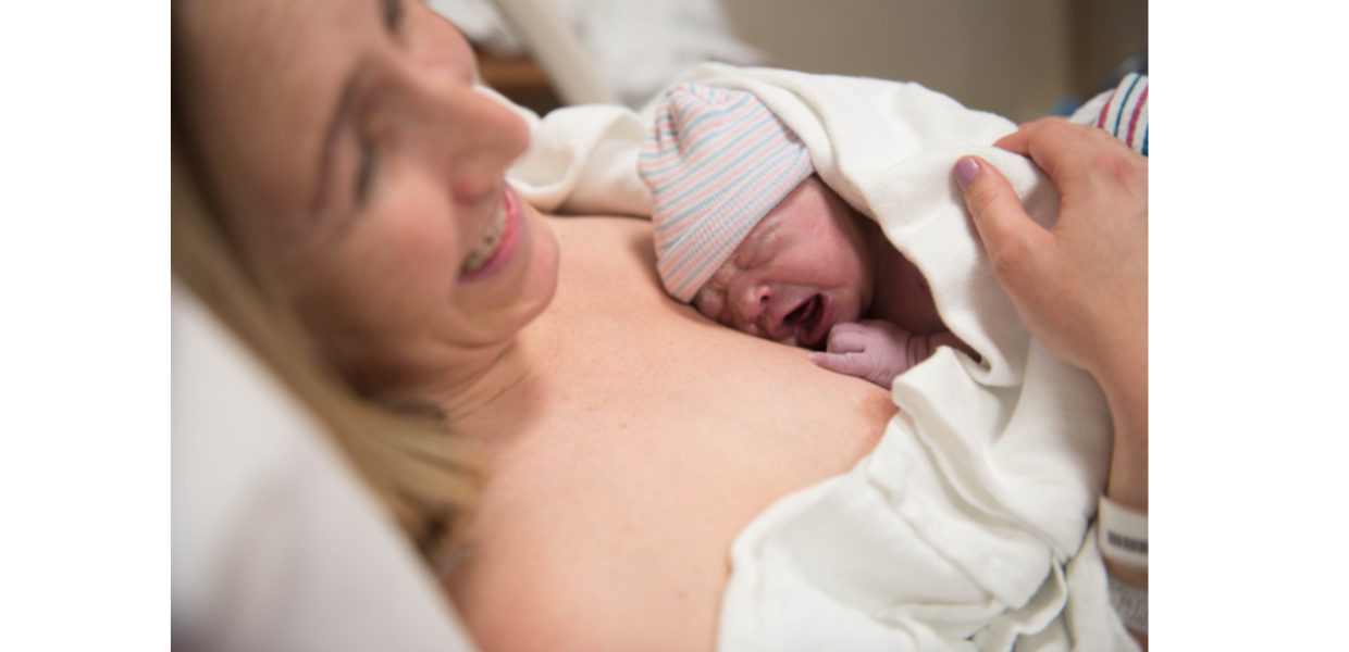 A woman lying on a bed holding a new born baby