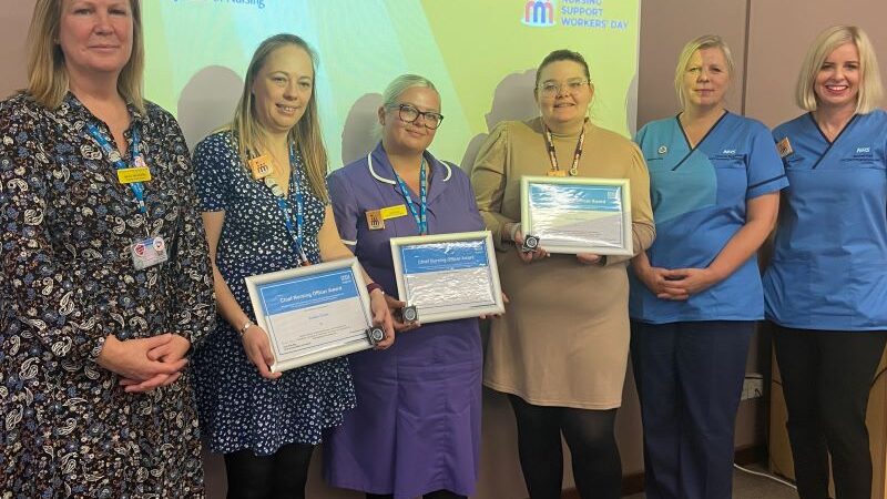 A line up of people standing in front of a screen which says Nursing Support Workers' Day.
