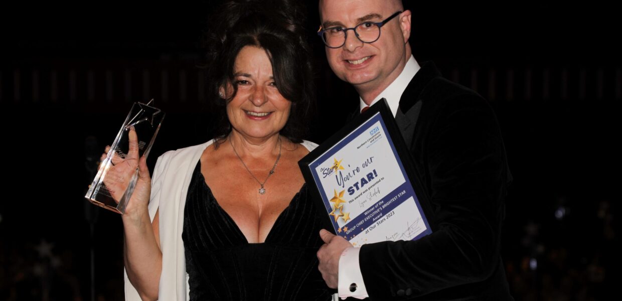 a smiling woman holds a trophy proudly as a man hands her a certificate
