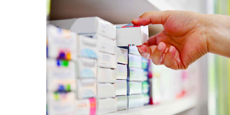 a hand grabbing a pack of medicines off a shelf