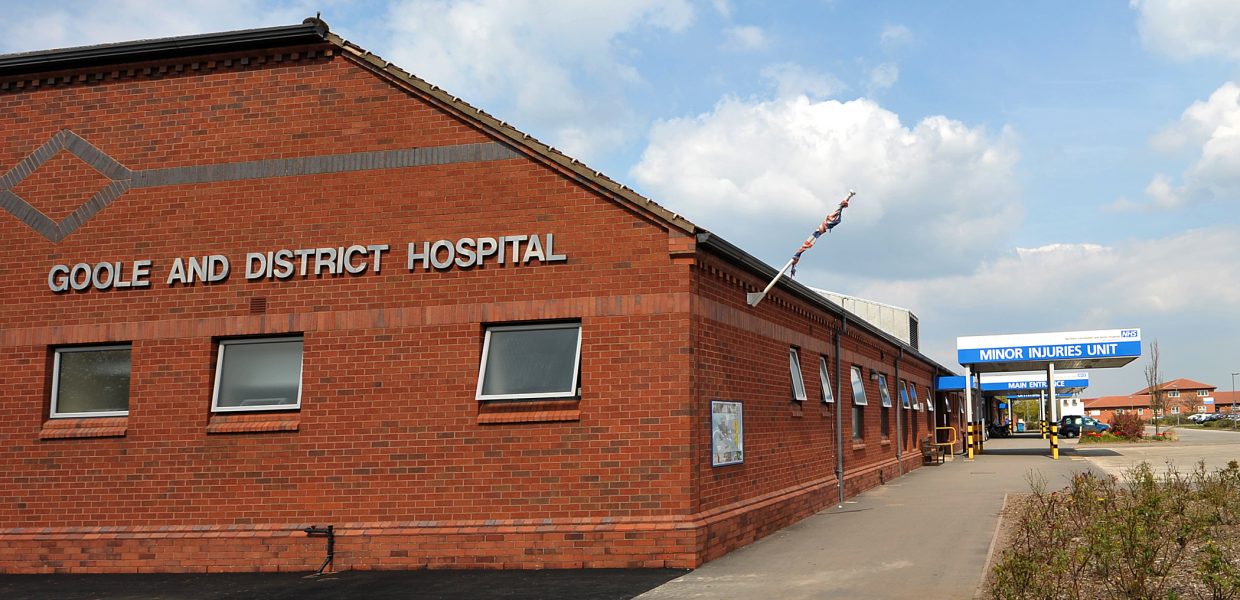 The exterior of Goole District Hospital. The name of the hospital can be seen on the red brick building and a path is leading towards a blue canopy.