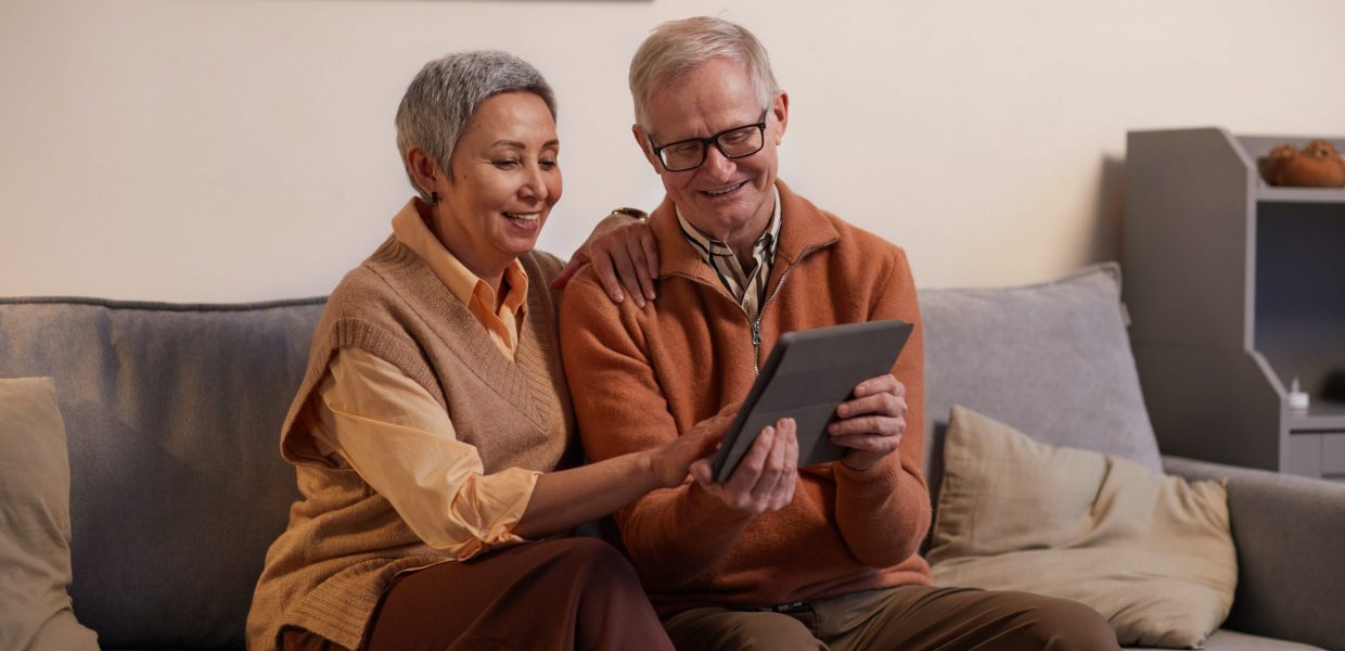 Older couple sitting on a sofa looking at a tablet
