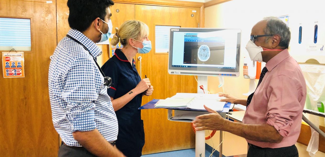 Three staff on the stroke ward at Grimsby hospital are looking at a scan on a computer on wheels