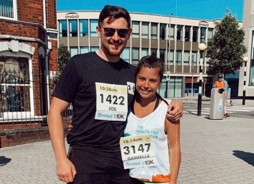 A man and a woman stood outside wearing running gear.