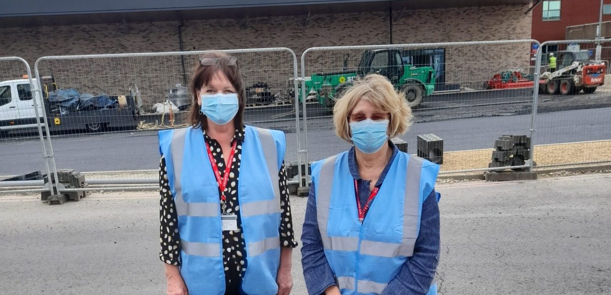 Volunteers Elaine and Jenny stood outside the new Emergency Department during its build